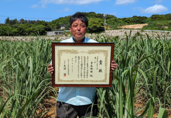 <平良さん、さとうきび畑を背景に>